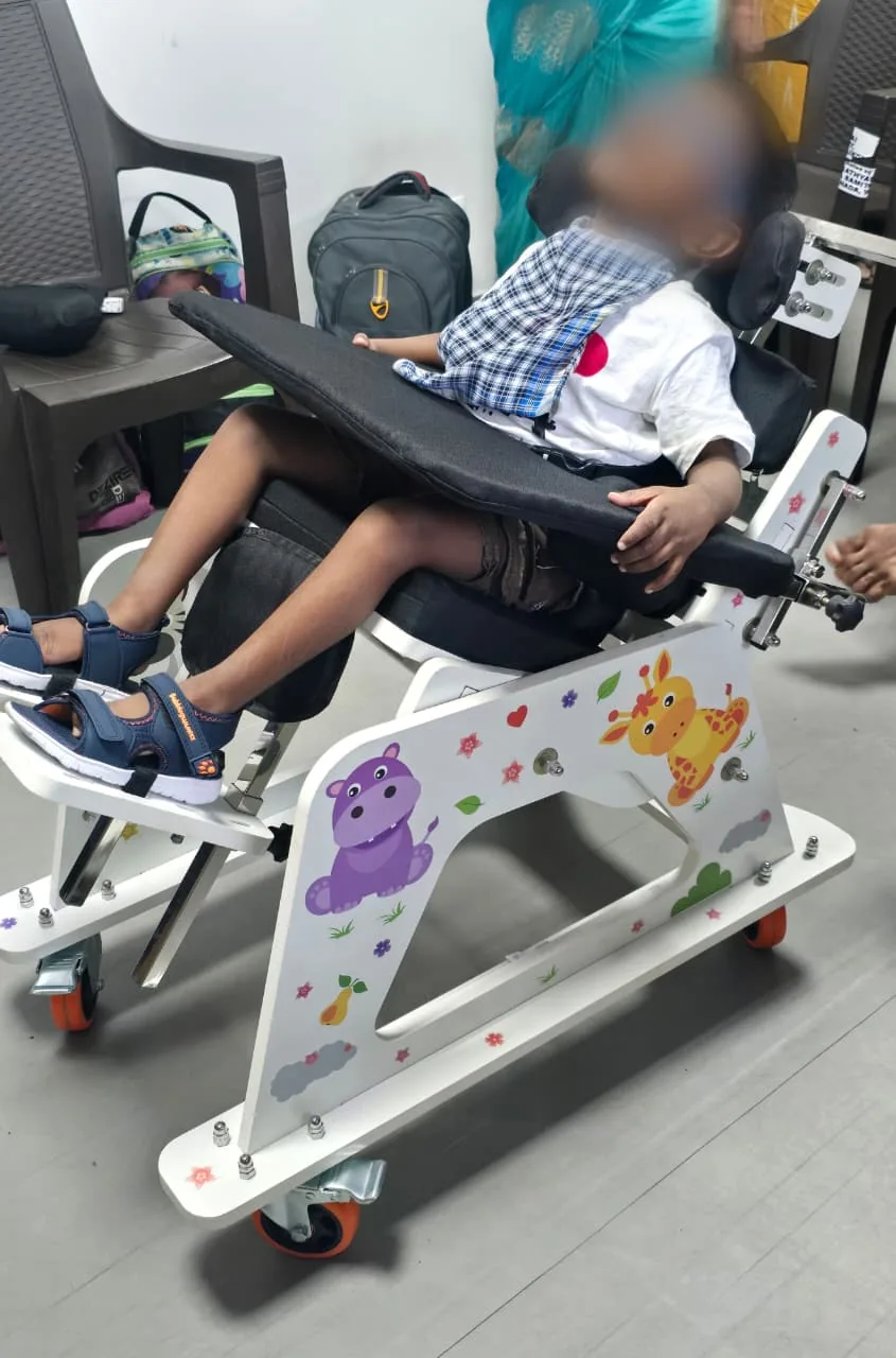 A child seated in a Modo chair during a fitting session, face obscured